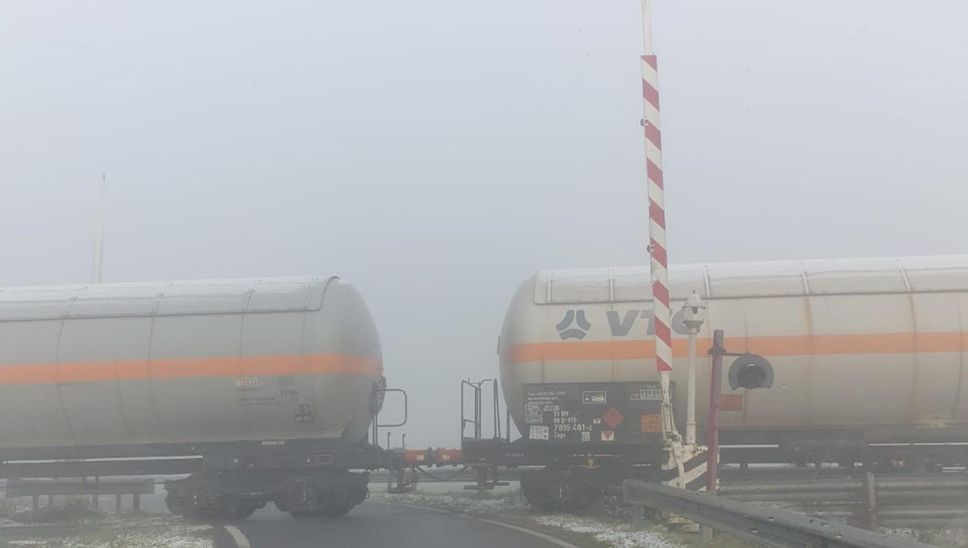 La foto scattata mentre il treno transita nella nebbia con il passaggio a livello alzato e il semaforo spento La foto scattata mentre il treno transita nella nebbia con il passaggio a livello alzato e il semaforo spento