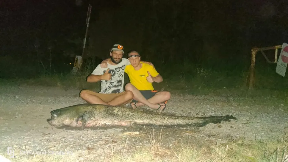 I due amici con il maxi siluro catturato nelle acque del canale Belgiardino