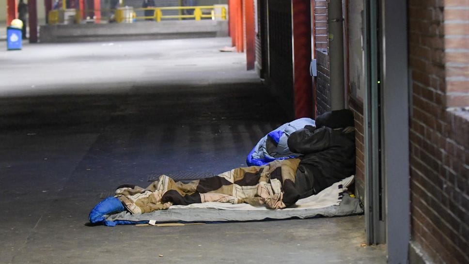 Un senzatetto affronta la notte sotto una pensilina