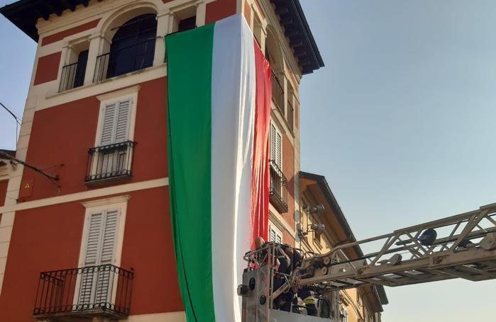 I vigili del fuoco srotolano un tricolore dalla torretta (Brandazzi)